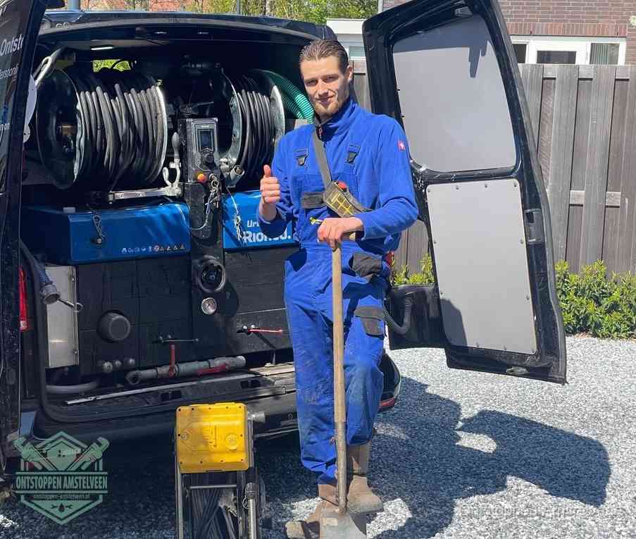 Een tevreden monteur met opgestoken duim naast de bestelbus, slim ingrijpen bespaart kosten bij een verstopte afvoer in Amstelveen
