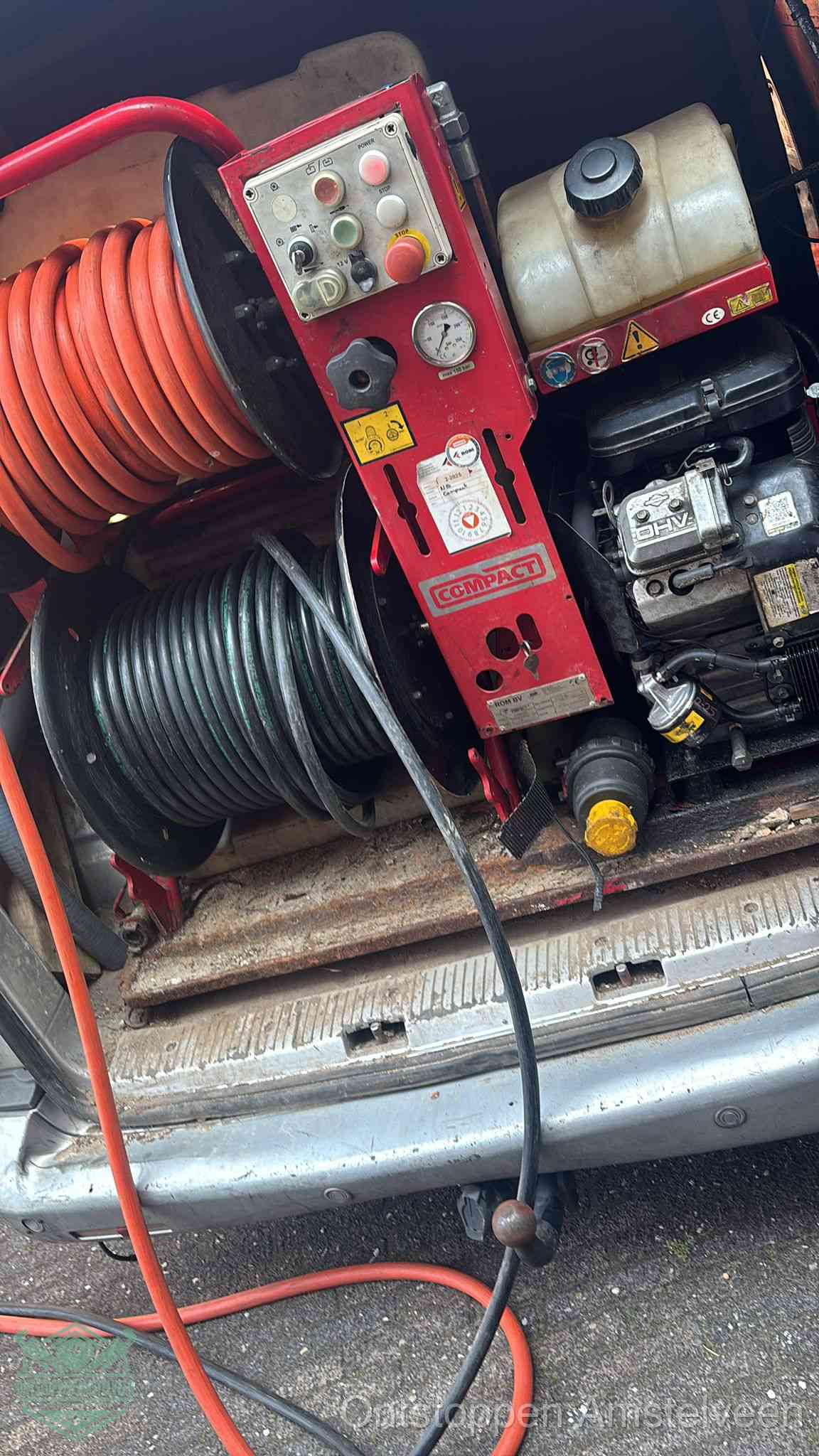 Een rood hogedruk-rioolreinigingstoestel in de laadbak van de bedrijfsbus, apparatuur voor een hardnekkige afvoerverstopping in Amstelveen