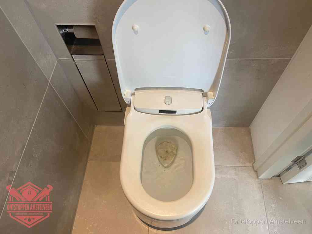 Een wit hangtoilet waarin een prop wc-papier op het water blijft drijven, een duidelijk signaal van een verstopte wc in Amstelveen