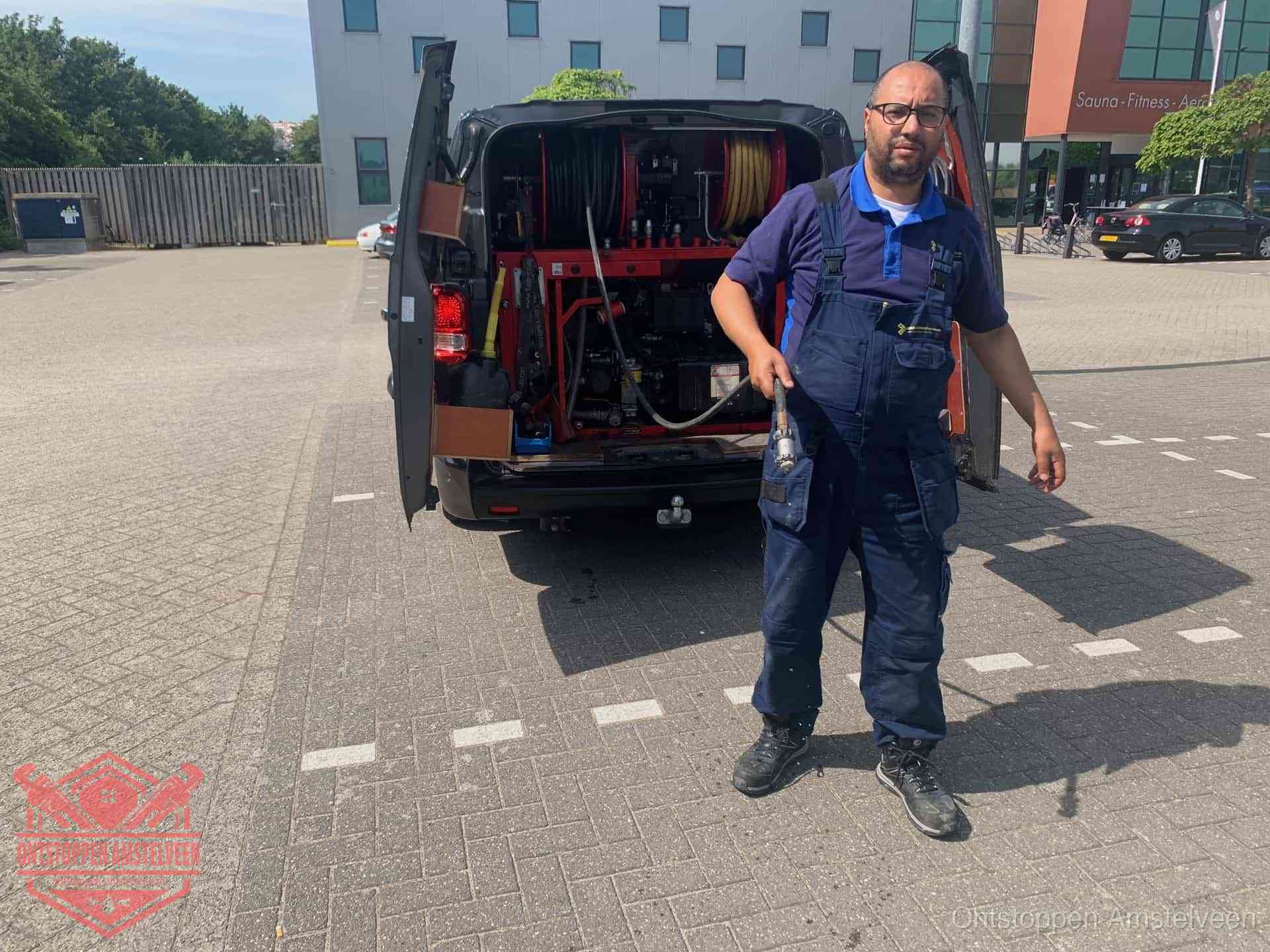 Een monteur bij zijn bestelbus met een hogedruk- en rioolreinigingsunit, klaar om de oorzaak van terugkerende wc-verstoppingen aan te pakken in Amstelveen