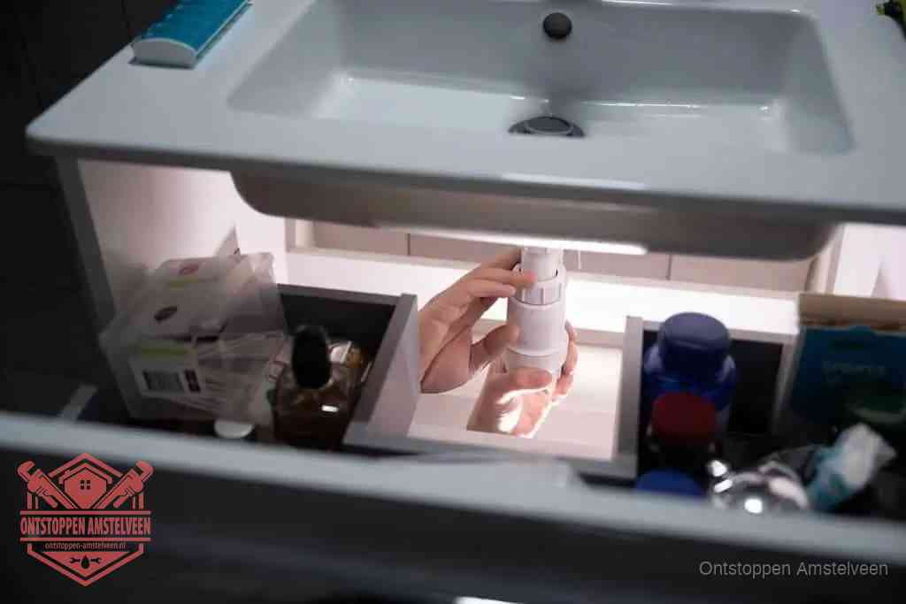 Een pompfles met zeep boven een wastafel in de toiletruimte, de warm water en afwasmiddel-methode om de wc te ontstoppen in Amstelveen
