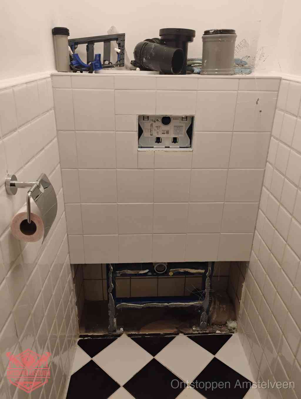 Een toiletruimte waar het hangtoilet en de inbouwreservoir-onderdelen zijn vrijgelegd voor onderhoud, periodiek nazicht voorkomt een wc-verstopping in Amstelveen
