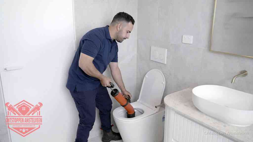 Een monteur gebruikt een handmatige perspomp (toiletontstopper) op een wandcloset tijdens het professioneel wc ontstoppen in Amstelveen