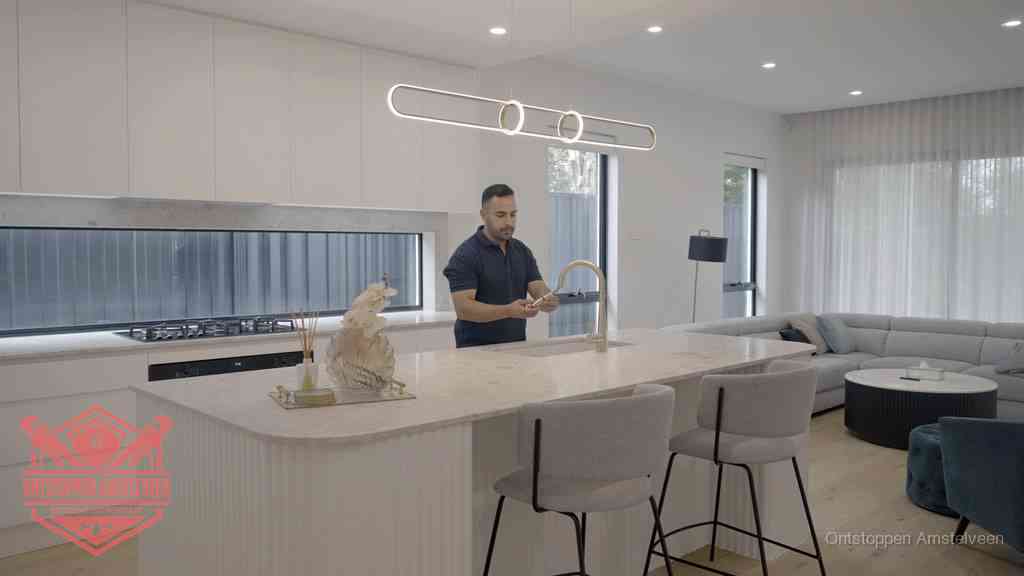 Een bewoner bij de keukenspoelbak die zelf aan de slag gaat met een verstopte gootsteen in Amstelveen